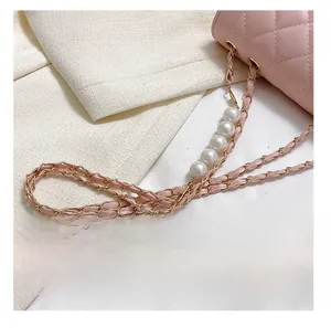 Detail of pink quilted shoulder bag featuring gold chain and five large white faux pearls