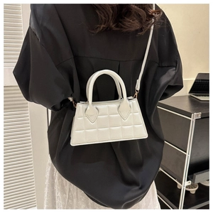 Petit sac blanc matelassé avec doubles poignées et bandoulière porté par un modèle