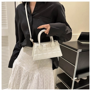 Détail du sac à bandoulière blanc texturé avec détails dorés sur un mannequin