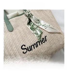 Détail du sac cabas en paille tissée beige avec poignées en cuir vert et foulard fleuri