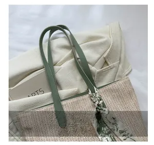 Détail d'un sac cabas tissé avec anses en cuir vert et foulard en soie à fleurs