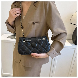 Detail der klassischen schwarzen Stepptasche mit Goldkettenriemen am Outfit des Models