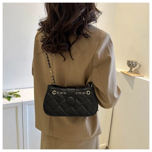 Detail der schwarzen Stepptasche mit goldener Kette und rundem Schnallenverschluss