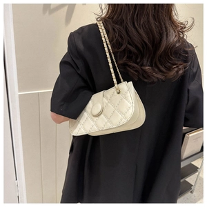 Detail der cremefarbenen Stepptasche mit Kettenriemen und rundem Knopfverschluss