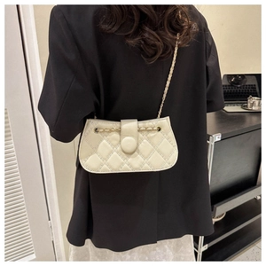 Beige Stepptasche mit Kettenriemen auf einem Schreibtisch im modernen Büroambiente