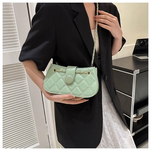 Details einer mintgrünen Stepptasche mit goldener Kette an einem eleganten Damenmodell