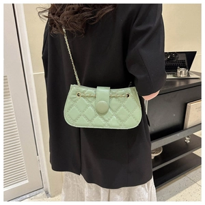 Nahaufnahme der hellgrünen Stepptasche mit goldener Kette auf einem schwarzen Blazer