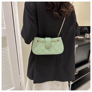 Nahaufnahme der minzgrünen Stepptasche mit Goldkette auf einem schwarzen Blazer