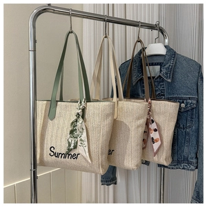Détail de trois sacs cabas en paille tressée avec broderie Summer et poignées en soie