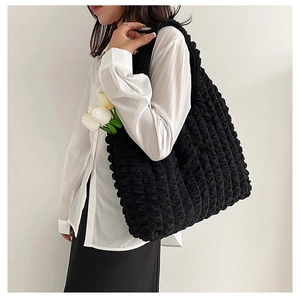 Detail of black puffy bubble texture canvas tote bag worn on shoulder by model