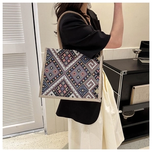 Detailed side view of an ethnic geometric canvas tote bag worn by a model