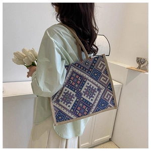 Detail of ethnic geometric tapestry tote bag featuring textured jute fabric and beige straps