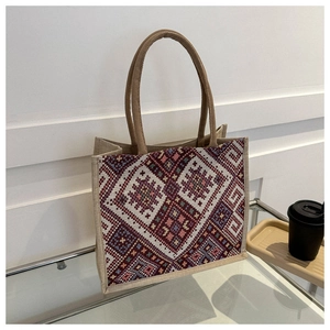 Detail of ethnic geometric canvas tote bag with brown handles on glass table