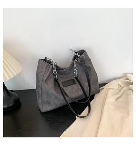 Detail of dark grey canvas tote bag with silver metal chain and leather shoulder strap