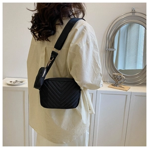 Detail of black quilted crossbody bag with adjustable wide strap and round coin purse pouch