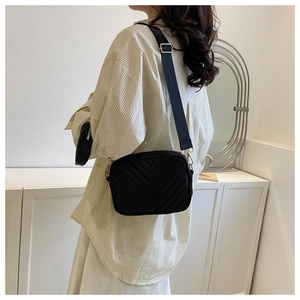 Detail of black V-quilted camera bag with wide strap and round coin purse attachment