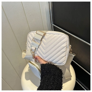 Detail of white quilted crossbody bag with V-shaped stitching and mini coin purse attachment