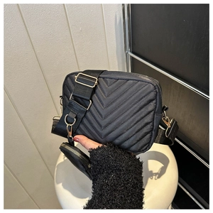 Detail of black quilted crossbody bag with golden hardware and round coin purse