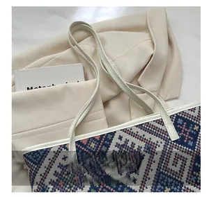 Close-up of geometric woven tote bag with colorful ethnic patterns and white leather handles