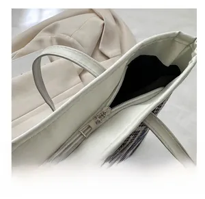 Detailed close-up of smooth silver metal zipper on geometric woven tote bag with white trim