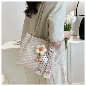 Detail of straw woven tote bag featuring 3D floral accents and a silk scarf handle wrap