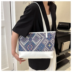 Detail of large tote bag featuring geometric patterned fabric and white leather accents