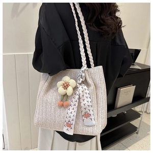 Close-up of woven straw tote bag with floral charm and patterned silk scarf detail