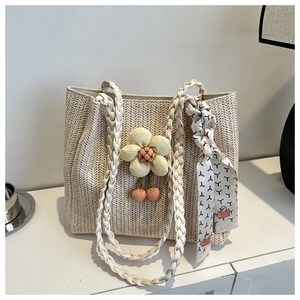 Detailed close-up of a woven cream tote bag with floral charm and patterned scarf