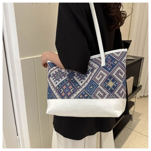 Detailed close-up of ethnic embroidery stitching and white leather on a large tote bag