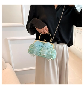 Detail of light green tweed handbag with blue tulle bow, pearls, and gold handle