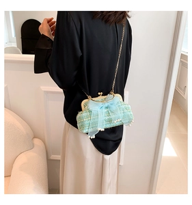 Detail of mint green tweed handbag with soft tulle bow and pearl accents on a gold chain