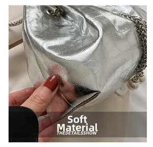 Macro detail of soft silver crocodile embossed bucket bag with pearl and chain accents