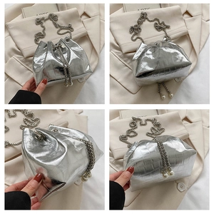 Detail of silver crocodile pattern bucket bag with pearl drawstring and chain strap