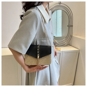 Detail of crossbody bag featuring black leather flap, straw texture, and gold tassel