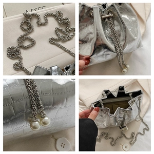 Detail of silver bucket bag with crocodile texture, metal chain and pearl pendant