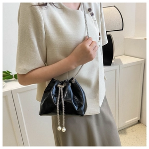 Detail of black crocodile pattern bucket bag with silver chain and pearl drawstrings