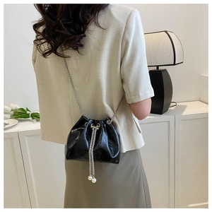 Detail of black croc-embossed bucket bag with silver chain and pearl charms