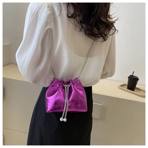 Detail of purple croc-effect bucket bag featuring drawstring and pearl accessories