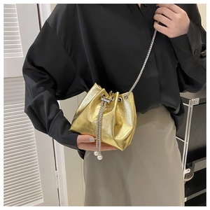 Detail of gold crocodile embossed bucket bag with pearl drawstring and metal chain strap
