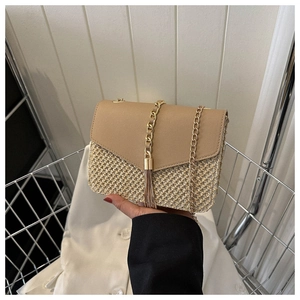 Détail du sac en paille tressée avec rabat en cuir kaki et pompon doré élégant