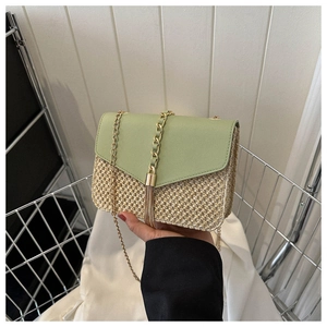 Détail du sac bandoulière en paille avec rabat en cuir vert et pompon doré chic