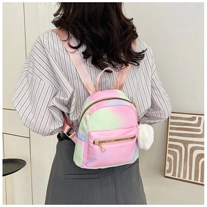 Detail of a mini gradient backpack featuring a soft white plush ball charm and gold zippers