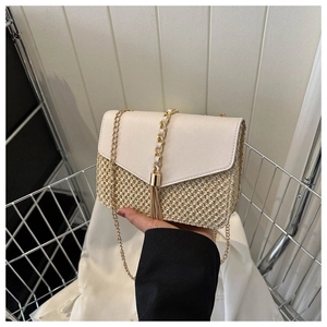 Détail du sac bandoulière en paille avec rabat blanc crème, chaîne dorée et pompon