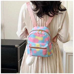 Mini tie-dye backpack with heart patterns and plush pendant shown on model back