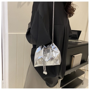 Silver metallic drawstring bucket bag featuring pearl charms and delicate chain strap