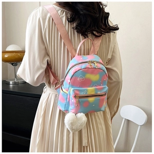 Detail of mini tie-dye backpack with love print and plush heart charm on model