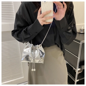 Detail of silver metallic drawstring bucket bag with chain strap and pearl accents
