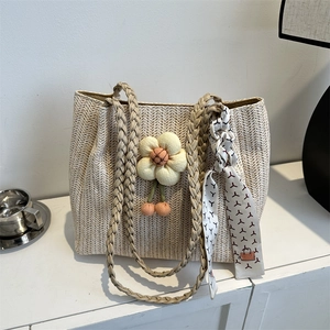 Minimalist woven tote bag with floral pendant and patterned silk scarf detail