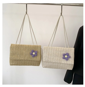 Dettaglio di borse in paglia intrecciata a V con fiore all'uncinetto e tracolla in corda