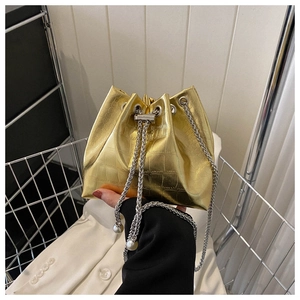 Detail of metallic gold crocodile textured bucket bag with silver chain and pearl charms